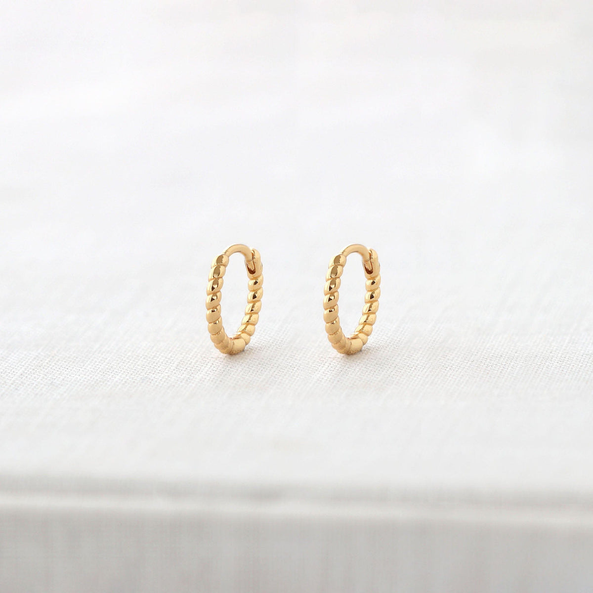 Kris Nations twisted hinged huggie hoop earrings in 18k gold vermeil